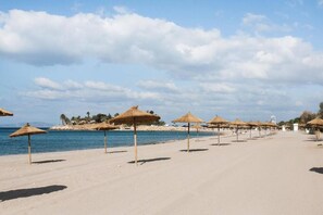 A beach with rows of thatched umbrellas and a clear view of the sea. - 3BD Luxury Sea View Penthouse Downtown by The Olon (Glyfada)