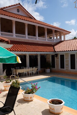Relax by the serene pool surrounded by lush greenery and Mediterranean-inspired architecture.
