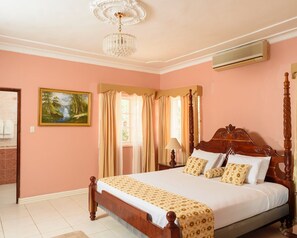 Classic bedroom with a large bed, chandelier, and framed artwork.