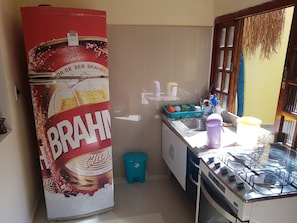 A compact kitchen with a refrigerator, sink, and gas stove.