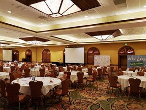 A conference room with round tables, chairs, and a large screen.