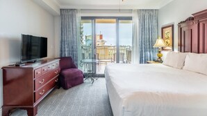 Een hotelkamer met een groot bed, een televisie, een dressoir, een stoel en een balkon met uitzicht.