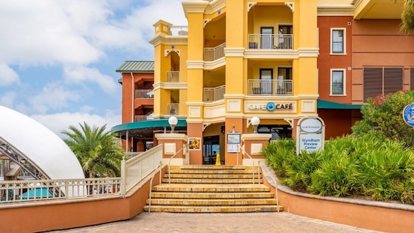 Entrada de hotel con cafetería, letrero de Wyndham Center y zona de piscina.