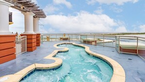 A pool area with a winding design, surrounded by a glass railing and a view of the sea. - Club Wyndham Emerald Grande - 1 Bedroom (Destin)
