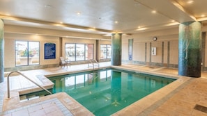 Una piscina interior con paredes de vidrio transparente, piso de baldosas y un cartel que indica ‘no buceo’.