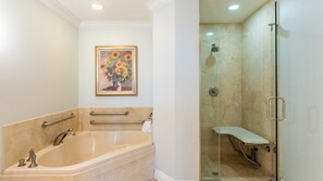 A bathroom with a bathtub, a glass shower enclosure, and a framed painting on the wall.