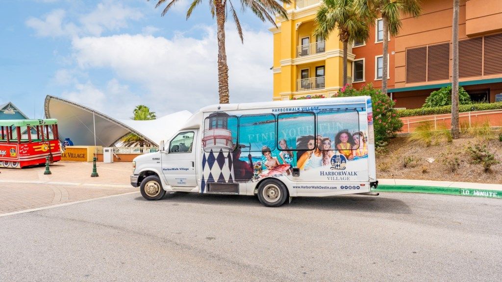 A white truck with advertising for Harborwalk Village parked on a street.