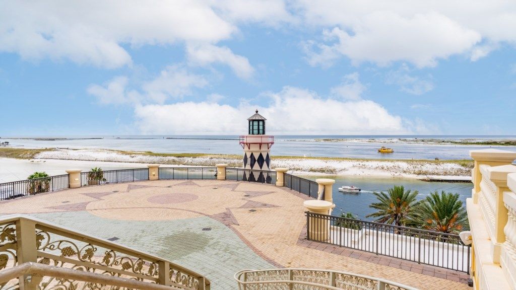Vista frente al mar con un faro, playa de arena y un área pavimentada con un diseño de estrellas.