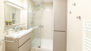 A modern bathroom with a glass-enclosed shower, a vanity with a mirror, and a towel rack.