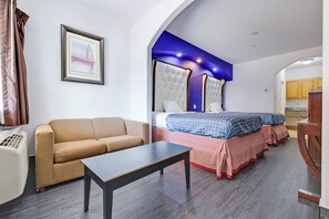 A bedroom with a sofa, a bed with patterned bedding, and a small table.