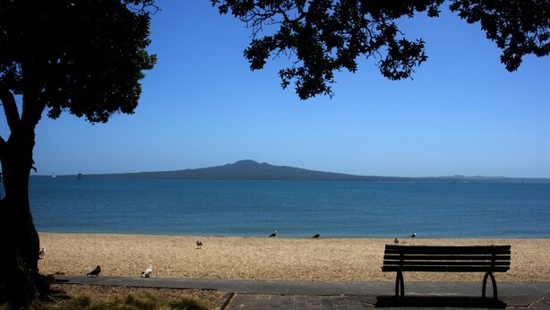 A beach with a bench and seagulls, a lighthouse, and a mountain in the distance. - In heart of mission Bay, Pet friendly, minutes walk to the beach (Auckland)