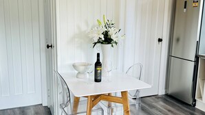 A modern kitchen with a white table, clear chairs, a white vase with flowers, a bottle of wine, and a refrigerator. - In heart of mission Bay, Pet friendly, minutes walk to the beach (Auckland)