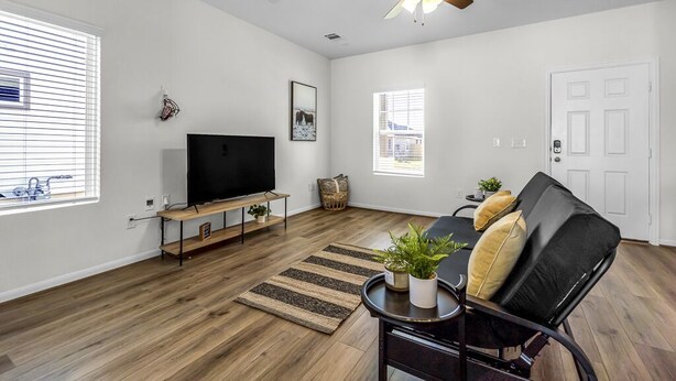 A spacious living room with a flat-screen TV, a ceiling fan, and a black leather sofa. - Single Family Home 25 Minutes from Downtown  (Hutto)