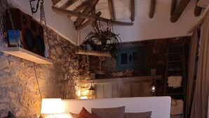 A cozy living room with a sectional sofa, a coffee table, and a stone wall. - Beautiful cottage tastefully decorated close to amenities (Chrani)