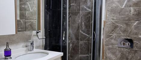 A modern bathroom with a curved glass shower enclosure, a white sink, and a toilet.