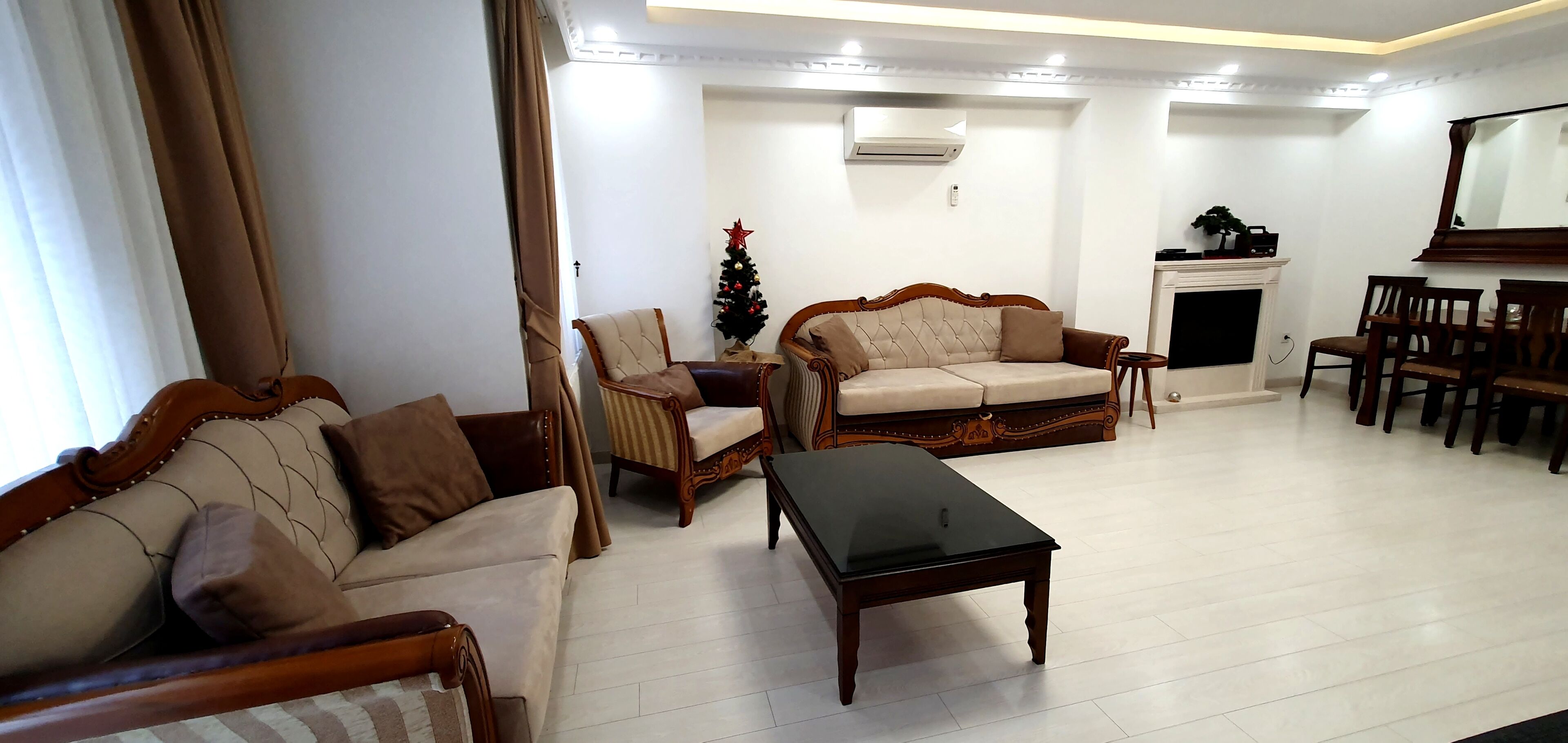 Un salon comprenant deux canapés, une table basse, une cheminée et un coin repas avec des chaises.
