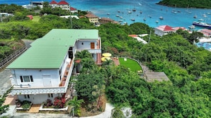 A coastal property with a large house, a swimming pool, and a view of the sea with boats. - Flamingo House • COCO • Ocean view • Walk to town (Cruz Bay)
