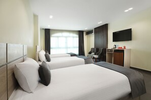 Ein Hotelzimmer mit zwei Betten, einem Schreibtisch, einem Stuhl, einem Fernseher und einem Fenster mit Vorhängen.