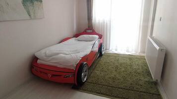 A bedroom with a bed, a radiator, a window with curtains, and a painting on the wall.