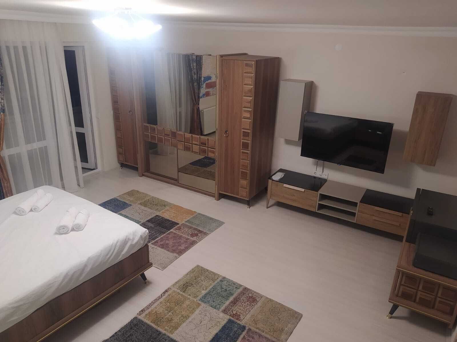 A hotel room with a bed, a TV, a wardrobe, and a small desk.