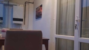 Habitació amb taula de dinar, una cadira, un quadre a la paret i una porta corredissa de vidre.