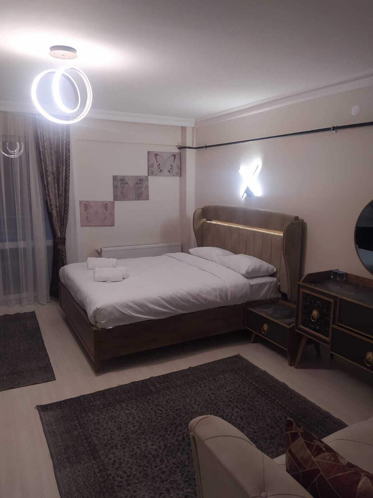 A bedroom with a bed, bedside tables, a mirror, and wall art.