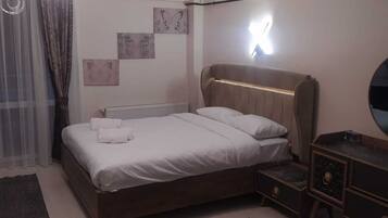 A bedroom with a bed, bedside tables, a mirror, and wall art.
