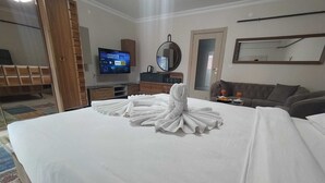 Habitació d'hotel amb un llit ben fet, una televisió penjada a la paret, un mirall i un sofà.