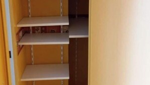 A closet with multiple shelves and hanging space, likely used for storage. - Apartment at the foot of DEAUVILLE/TROUVILLE (Touques)