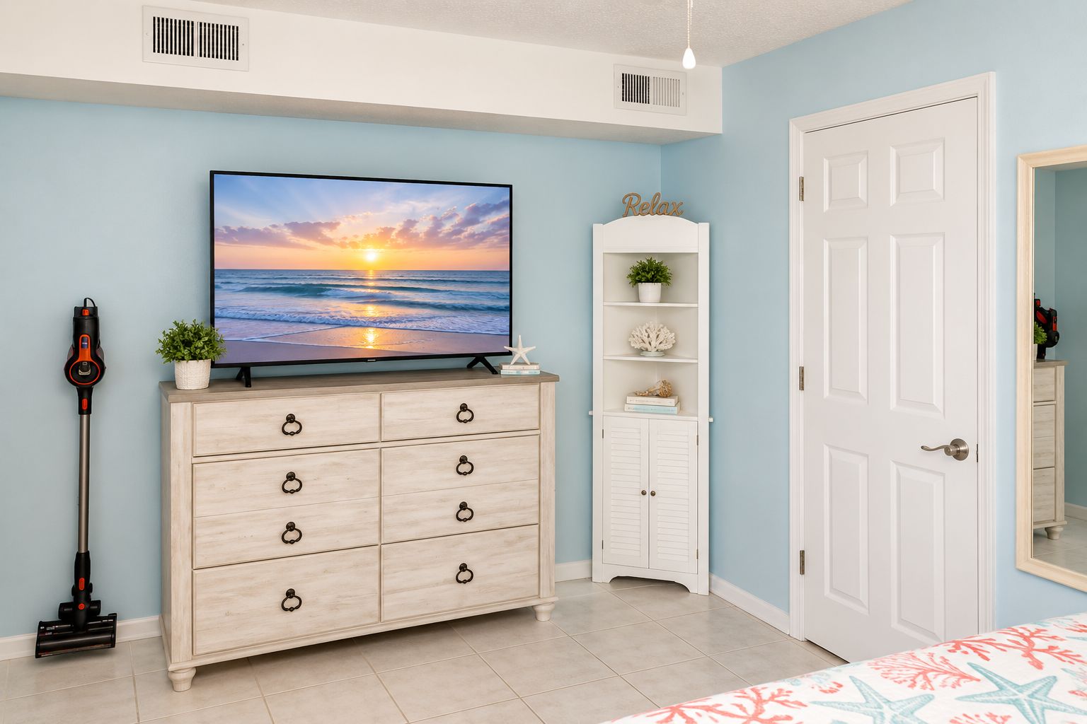 Ein Zimmer mit Fernseher, der einen Sonnenuntergang zeigt, einem Holzschrank, einer weißen Kommode und einer Tür.