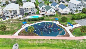 Vista aérea de una zona residencial con casas, un parque infantil y una masa de agua.