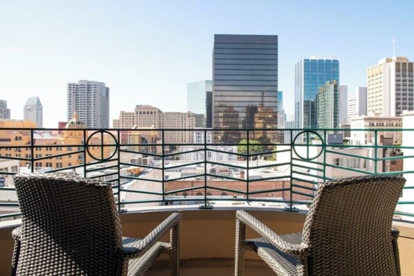 A balcony with wicker chairs and a cityscape view.