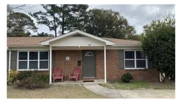 Situated on a quiet property, this charming house features a front porch with two chairs and a gabled roof.