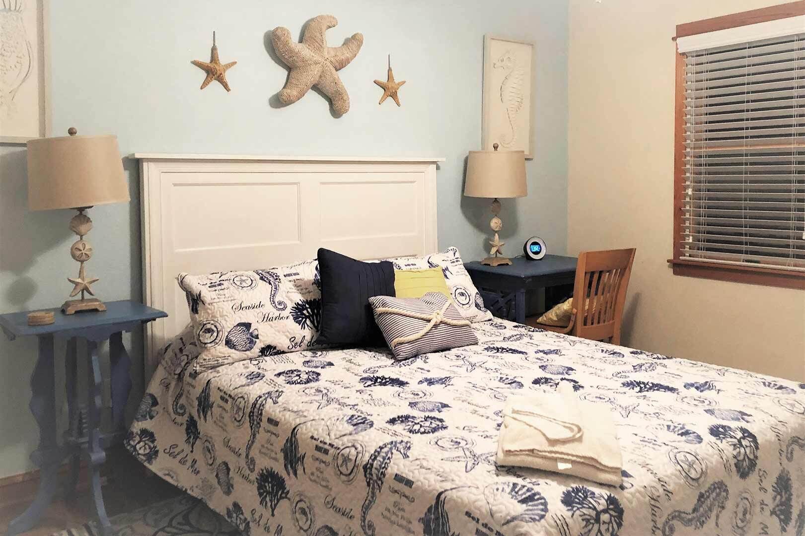 A bedroom with a bed, two nightstands, a chair, and a window with blinds.