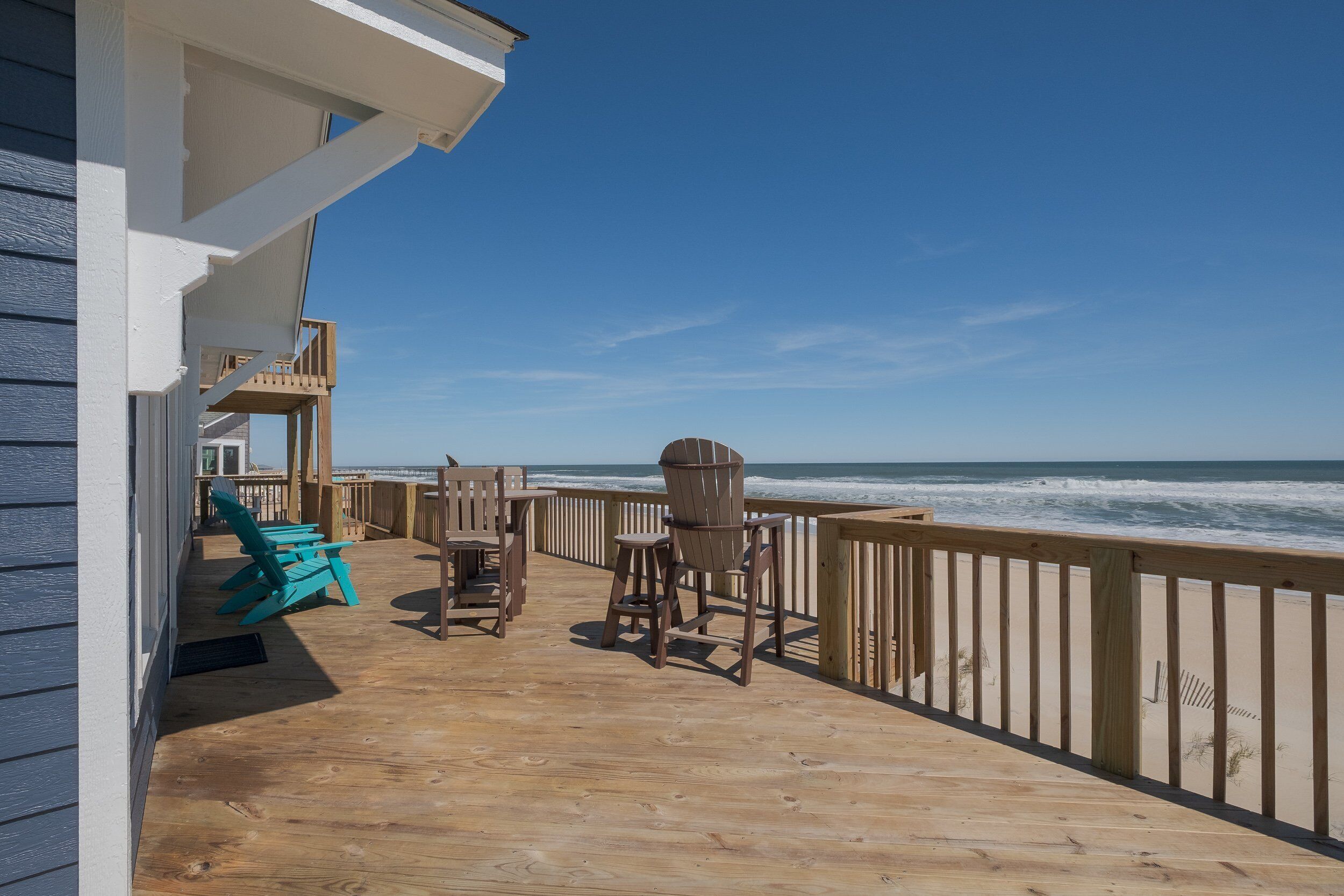 A wooden deck with outdoor seating and a view of the ocean.