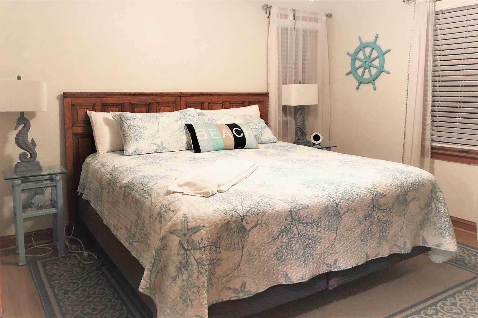 Uma cama com colcha florida, cabeceira de madeira e um volante de navio decorando a parede.