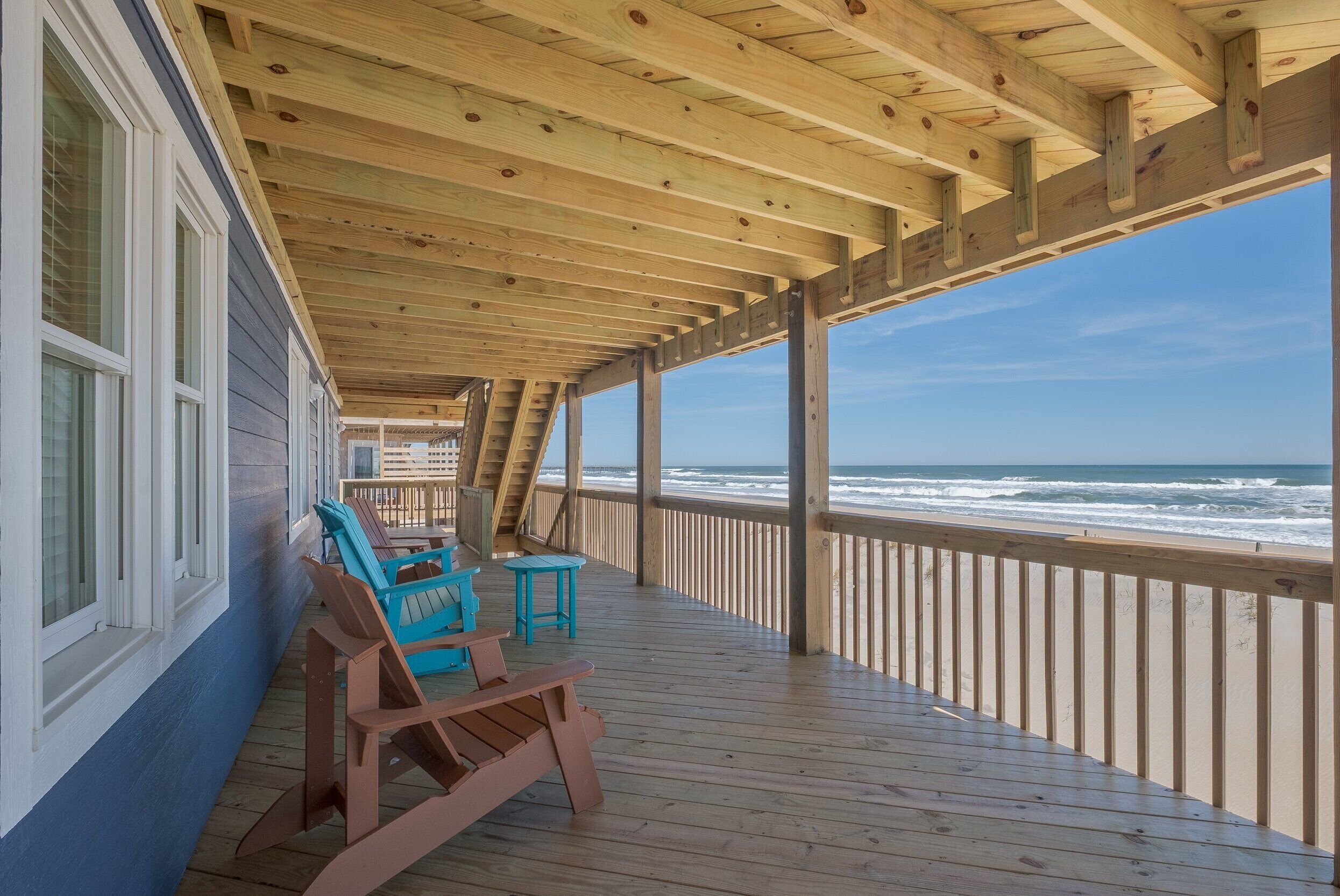 A wooden deck with a view of the ocean, featuring a railing and seating area.