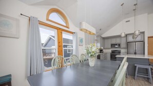 Eine moderne Küche mit Essbereich, großen Fenstern und Blick ins Freie.