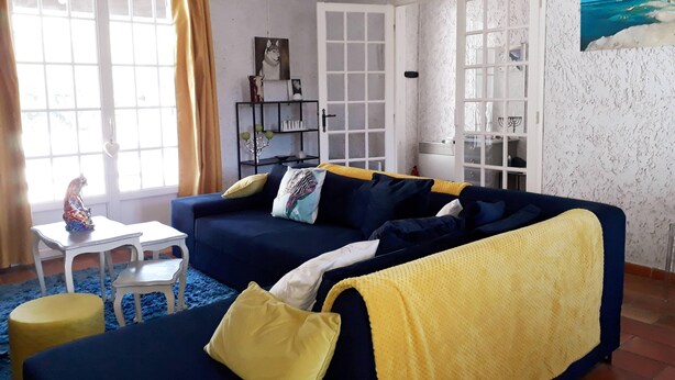 A living room with a blue sofa, yellow cushions, a small white table, and a blue rug. - Cozy villa in the heart of the Luberon (Apt)