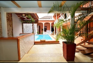 A pool area with a wooden deck, a palm tree planter, and a staircase leading to an upper level. - 7CA2-1 CASA DE LUJO EN CARTAGENA (Cartagena)