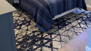 A bedroom with a bed, nightstands, a lamp, a window with blinds, and a patterned rug. - Newly Remodeled Midtown home 5 miles from PGA (Tulsa)