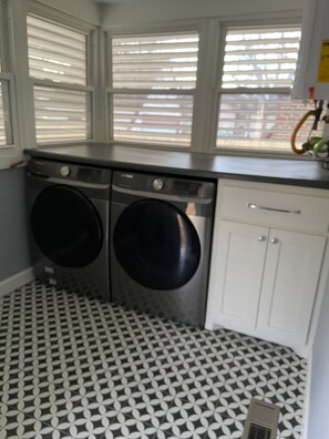 Een wasserette met twee wasmachines, een droger en een wit kastje.