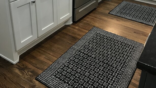 A kitchen with white cabinets, a stainless steel oven, and black and white patterned rugs. - Newly Remodeled Midtown home 5 miles from PGA (Tulsa)