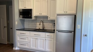 A modern kitchen with white cabinets, a stainless steel refrigerator, and a microwave. - Newly Remodeled Midtown home 5 miles from PGA (Tulsa)