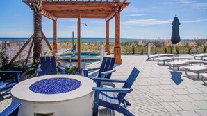 Eine Holz-Pergola, Sitzgelegenheiten im Freien, eine Feuerstelle und Meerblick.