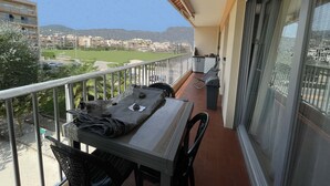 A balcony with a table, chairs, and a view of a cityscape and mountains.