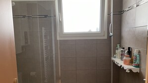 A bathroom with a shower, a toilet, a sink, and a window.