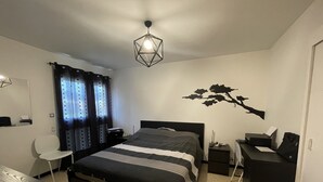 A modern bedroom with a bed, desk, chair, and a decorative wall piece.