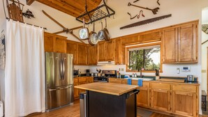 A kitchen with wooden cabinets, stainless steel appliances, and a wooden island.