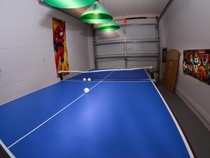 A blue ping pong table with a net, two white balls, and a green hanging lamp. - Great Community, amazing private pool, near Disney! (Davenport)